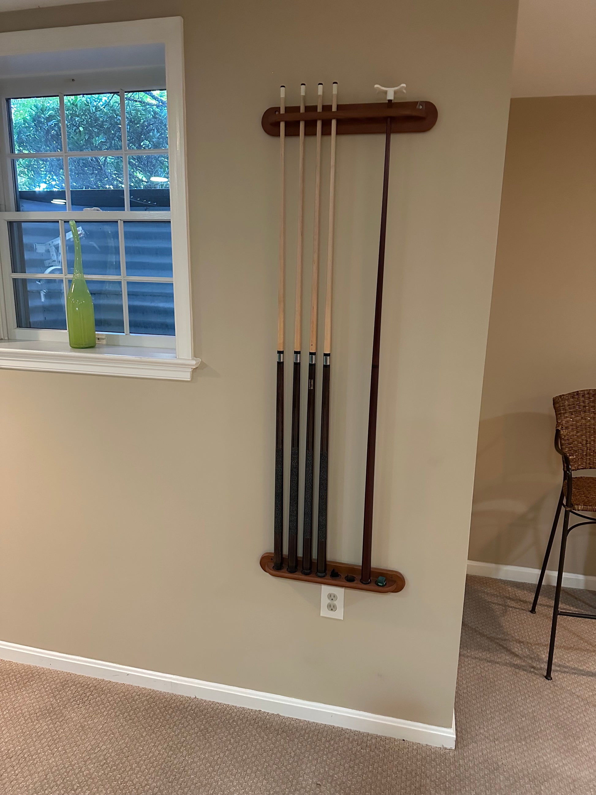 Set of pool cues on a wooden rack against a wall
