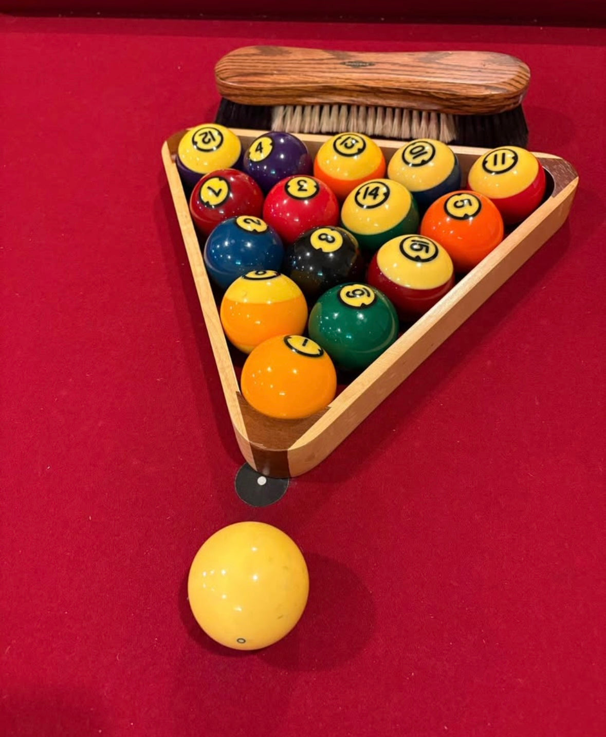 Set of billiard balls in a wooden triangle rack on red felt