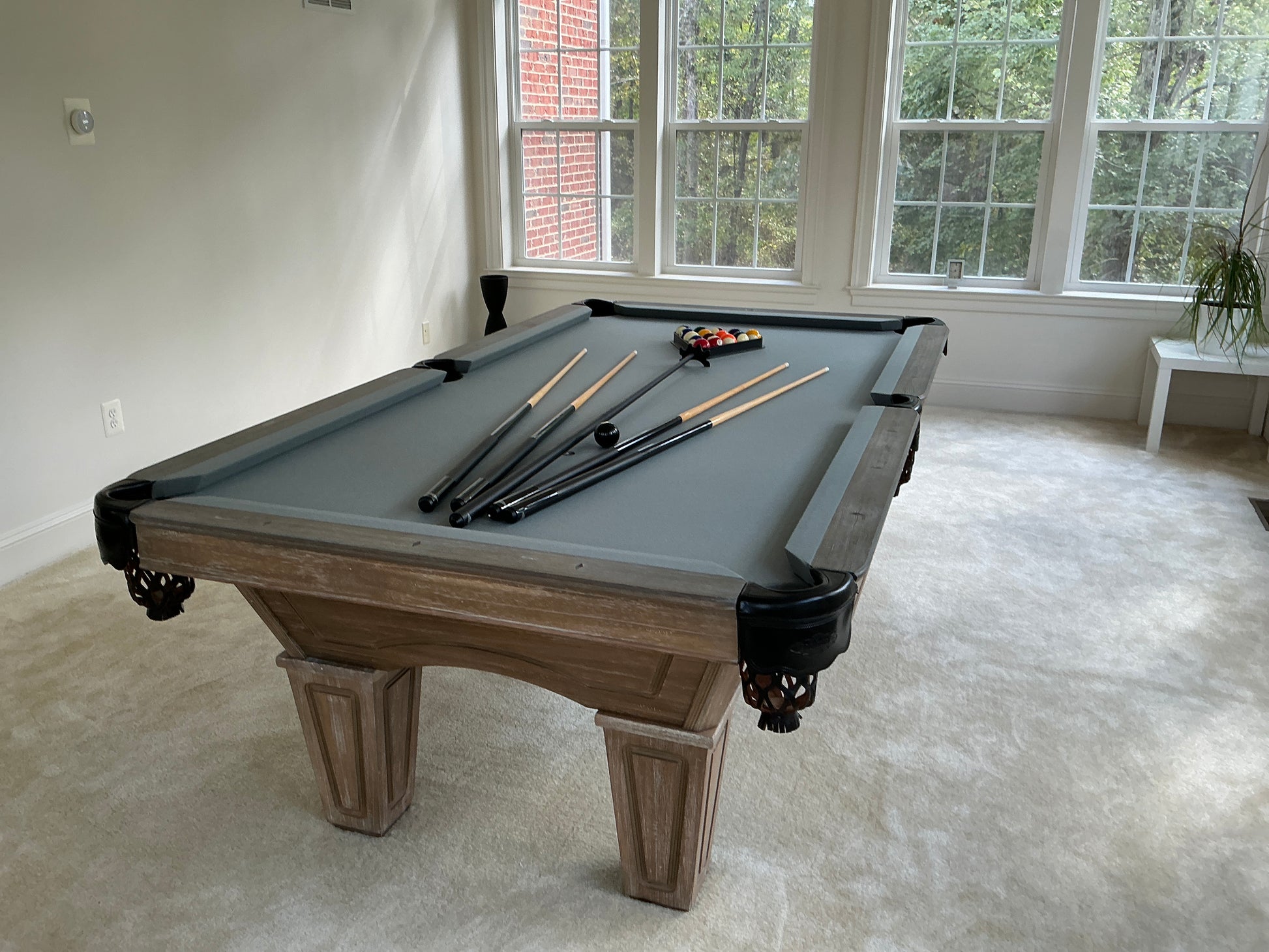 Pool table with grey felt with cues and balls