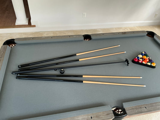 Pool table with grey felt with pool cues and balls