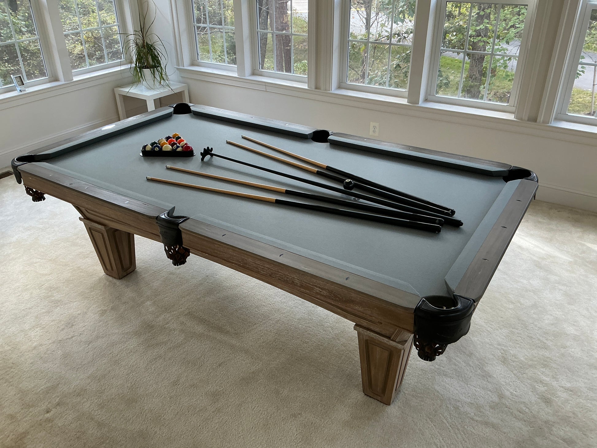 Pool table with grey felt with cues and balls