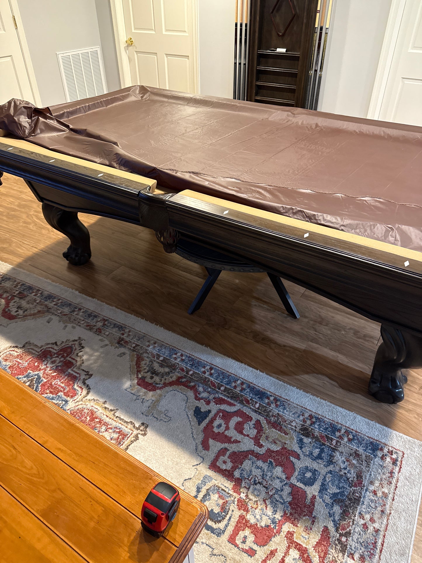 Pool Table cover on a pool table with a decorative rug and wooden floor in the background