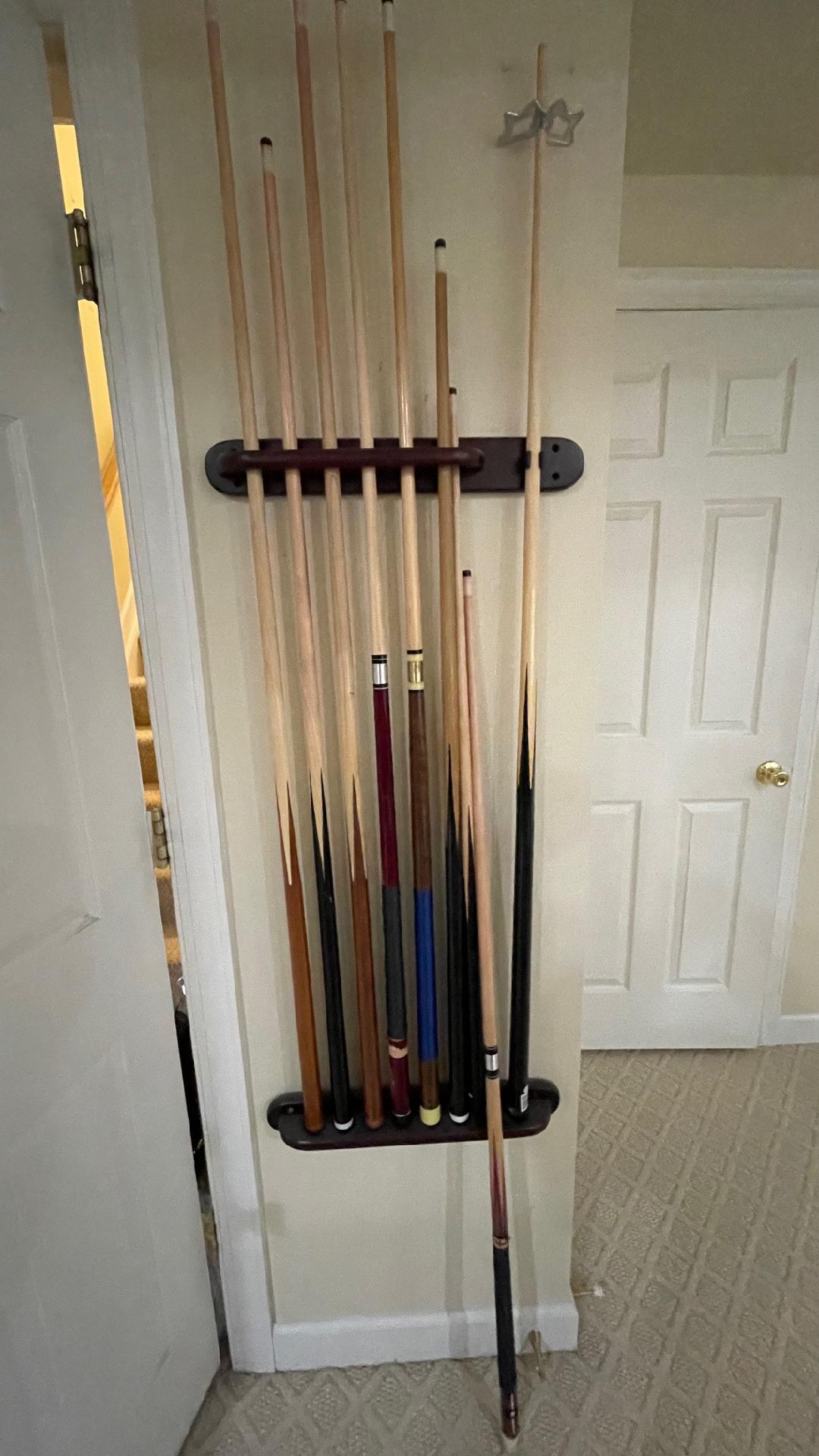 Set of pool cues leaning against a rack