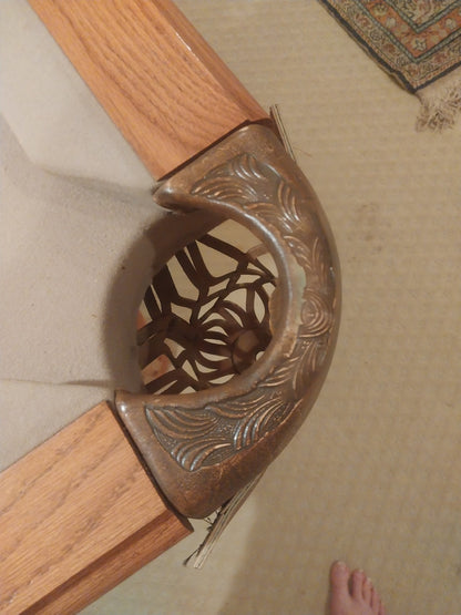 Decorative wooden chair leg with intricate carvings on a beige carpeted floor.