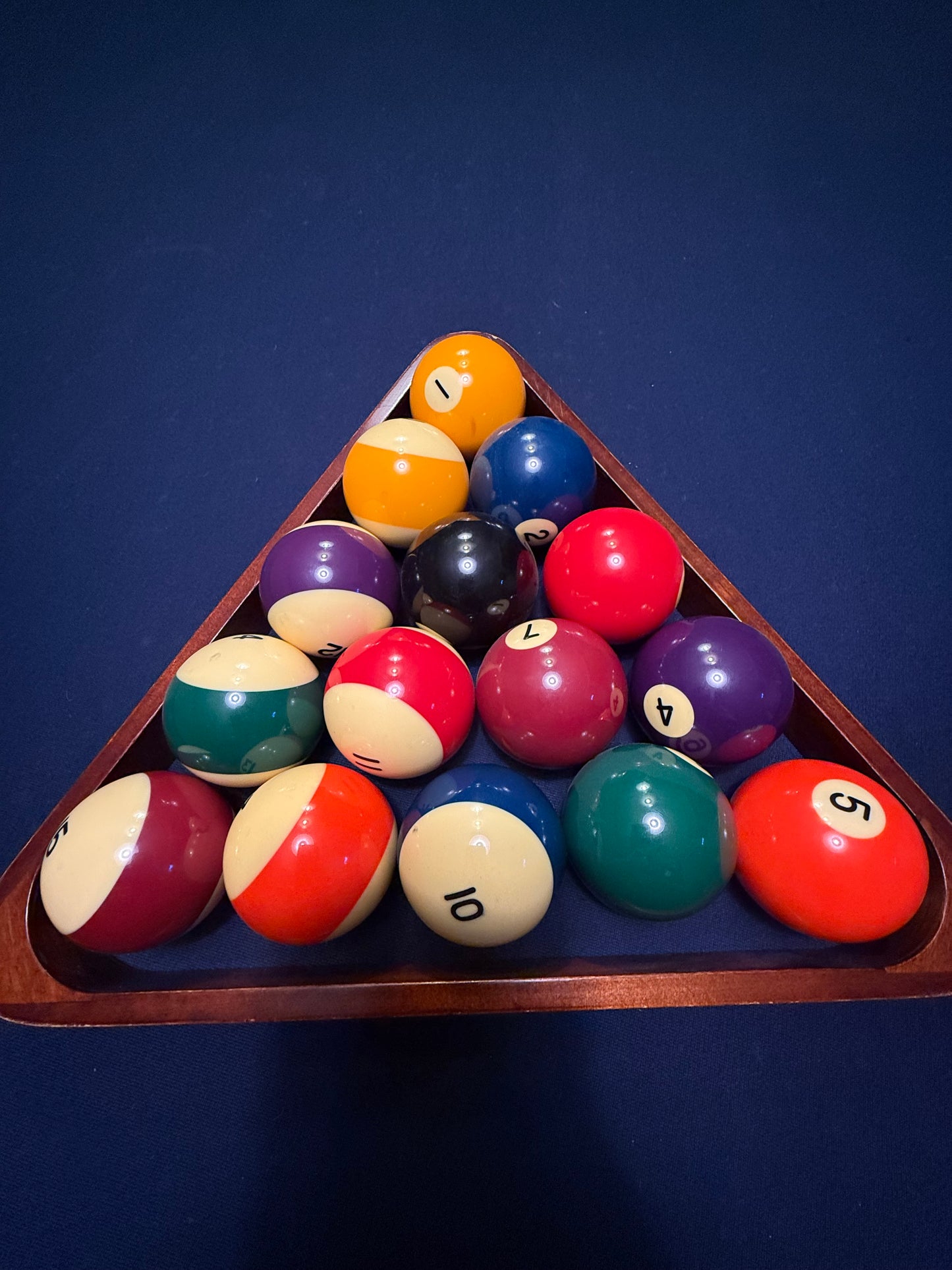 Set of billiard balls in a wooden triangle rack on a blue background