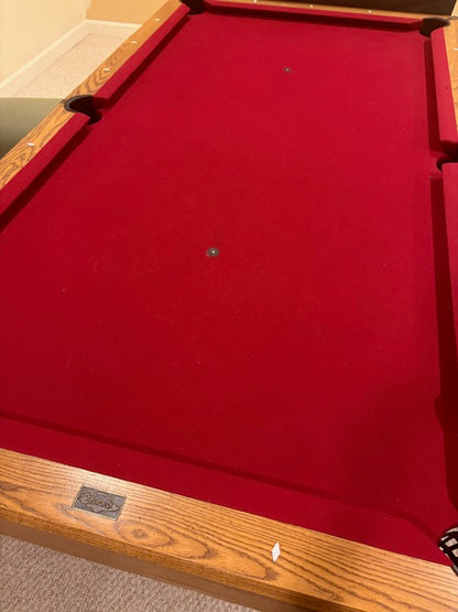 Red pool table with wooden frame and red felt