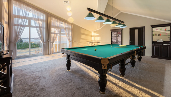 A pool table in a billiard room overlooking a lake