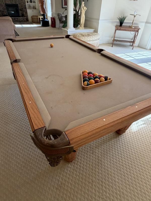 Pool table with balls and a billiard triangle in a living room setting