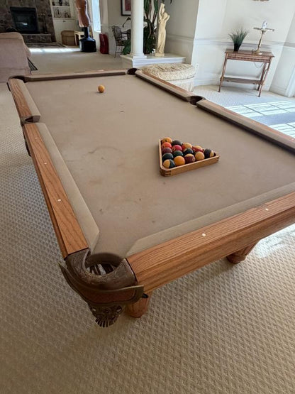 Pool table with balls and a billiard triangle in a living room setting